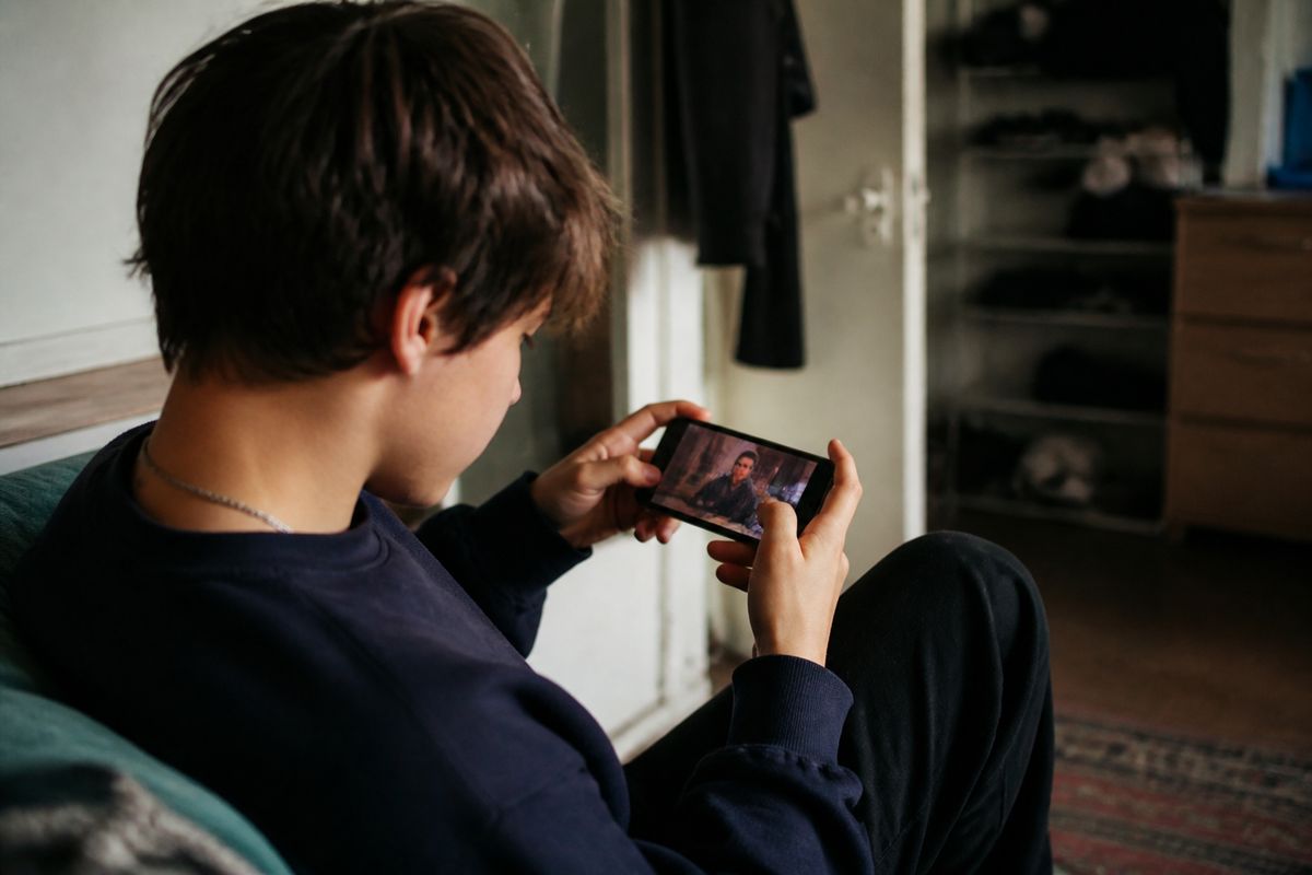 A young person watching BBC content on a smartphone.