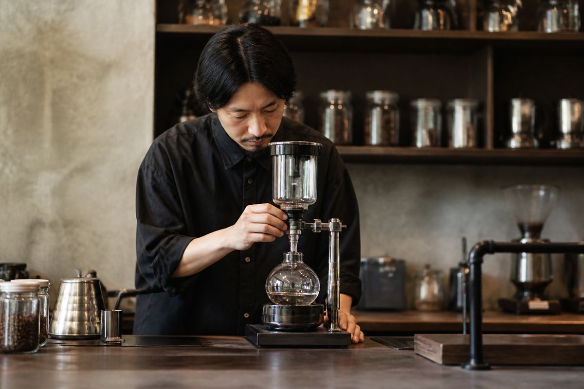 A barista adjusting a precision coffee brewer in a specialty café.