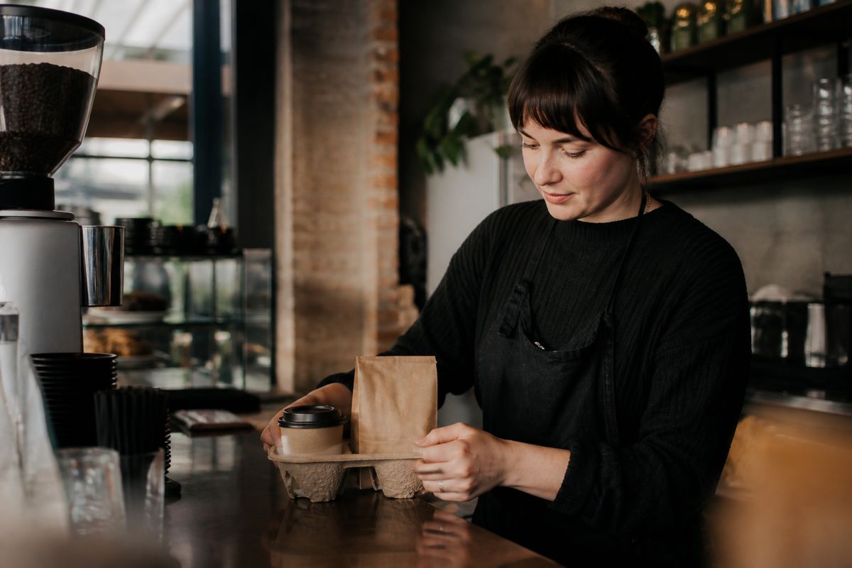 A barista carefully preparing a specialty coffee order for delivery