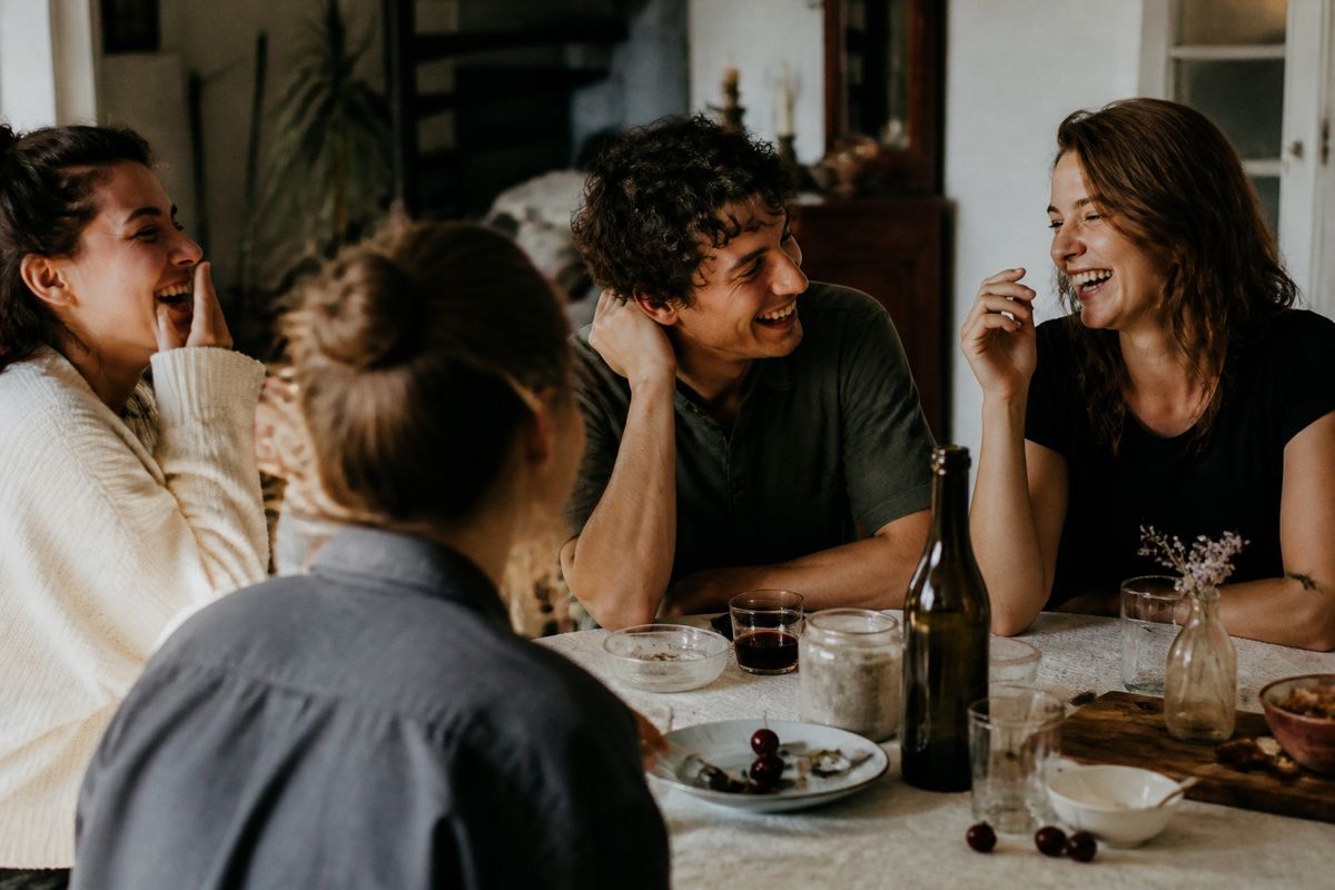 Friends gathered laughing around a table sharing stories.