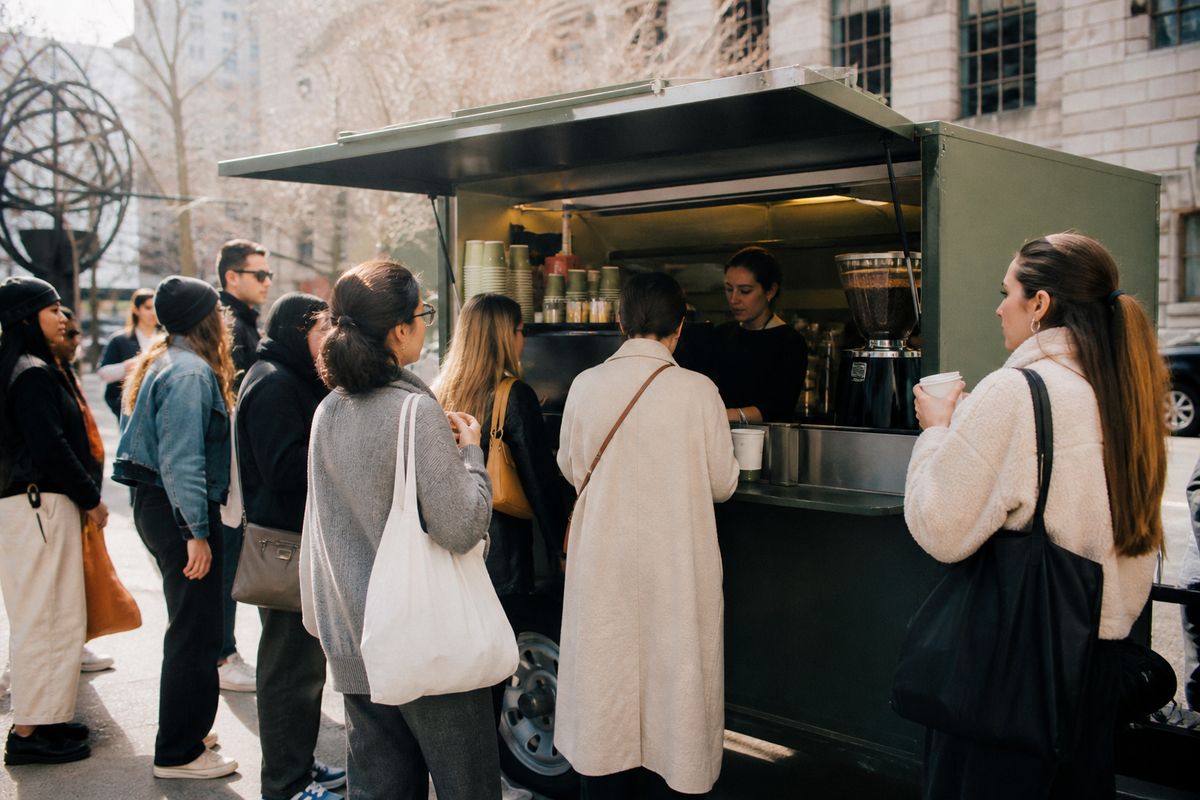 A Blank Street coffee cart bustling with customers on a city street