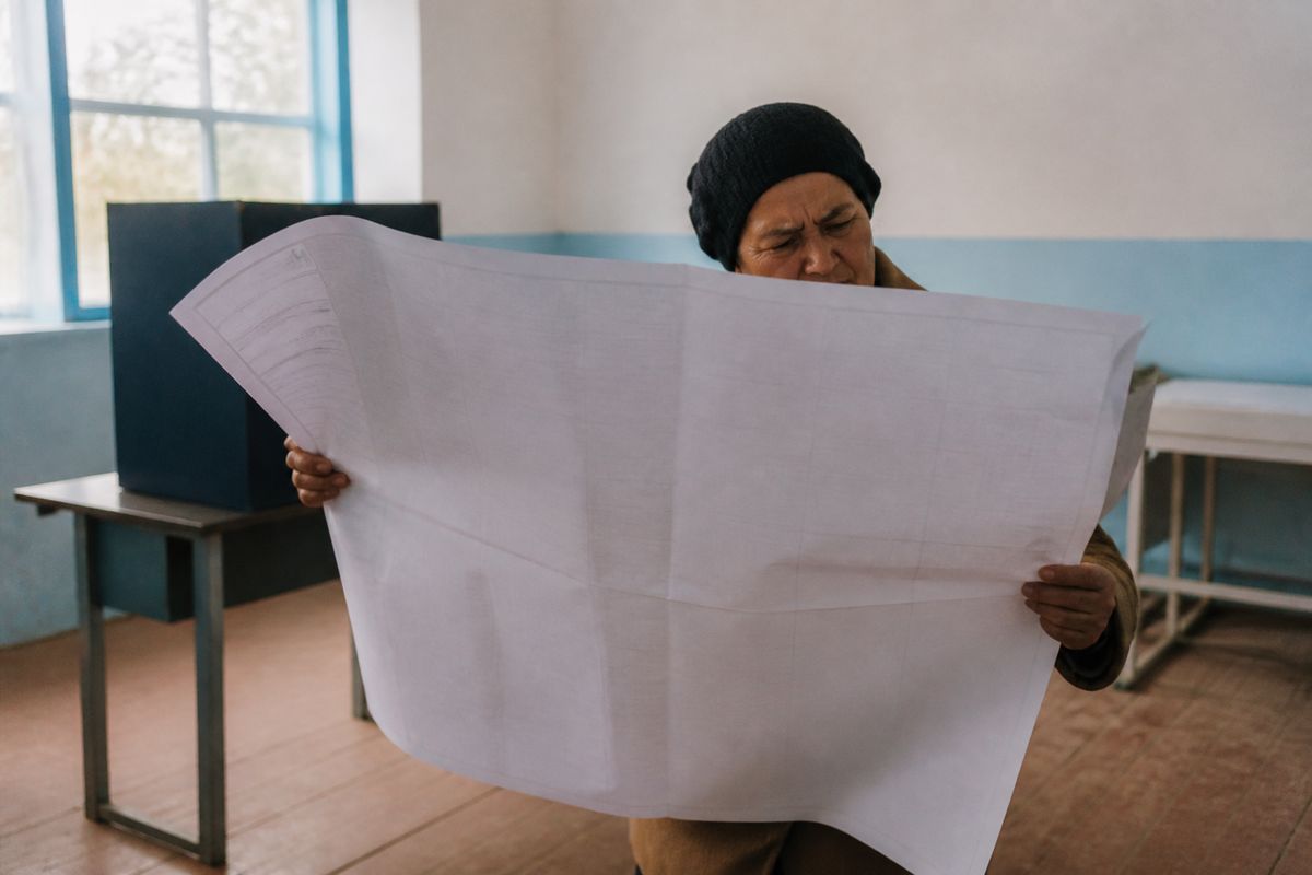 A voter struggles to handle an oversized ballot paper.