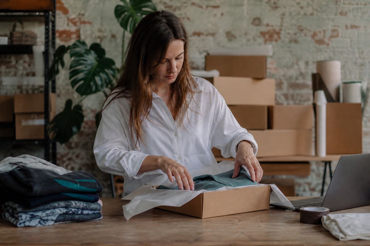 A small business owner packaging print-on-demand products at a desk