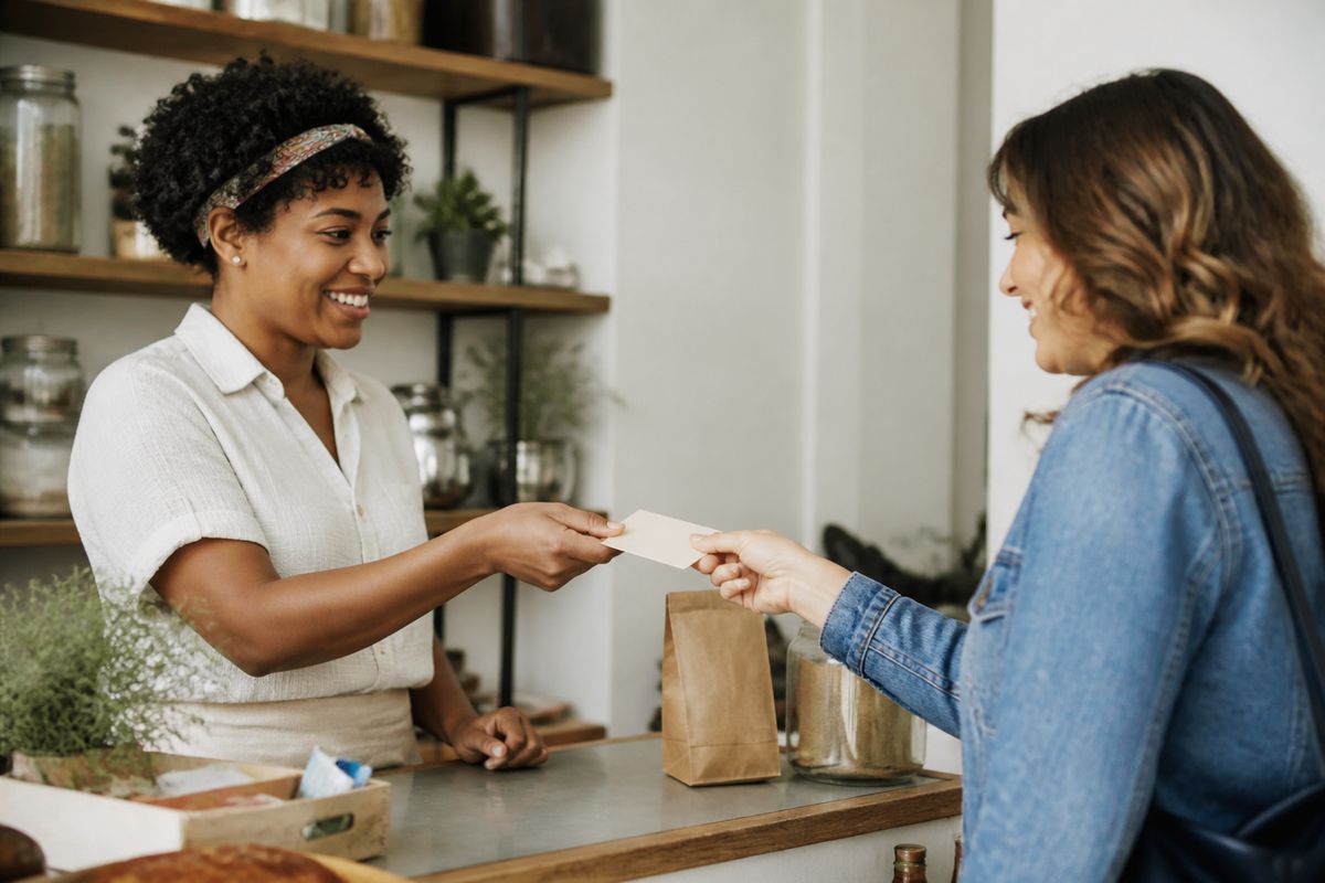 A small business owner handing a coupon to a smiling customer