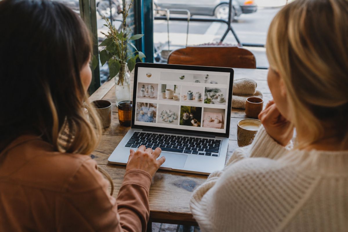 Shoppers browsing Etsy deals on a laptop at a café table