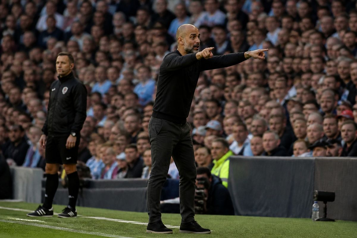 A football manager giving instructions during an early-season match