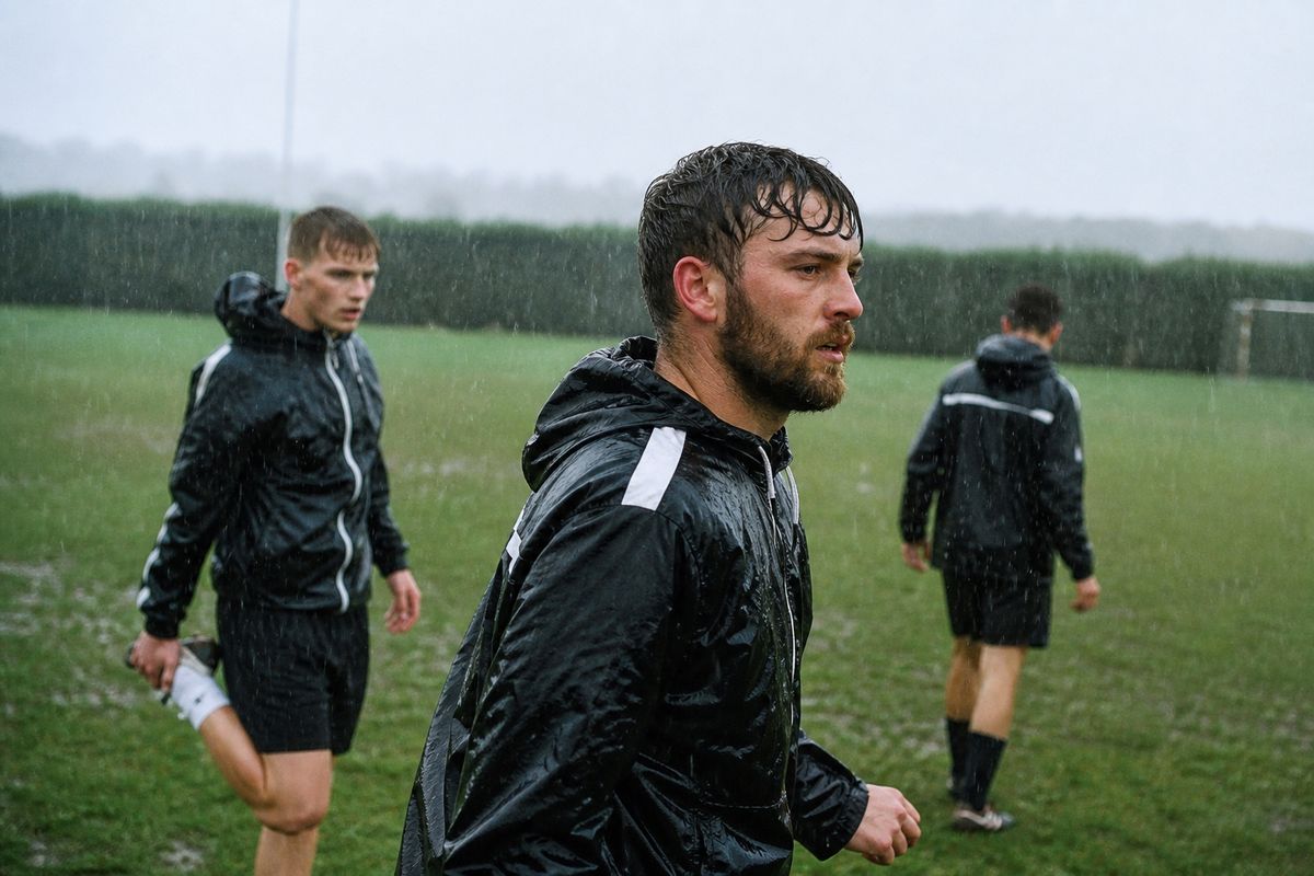 Non-league football players preparing on a rainy training pitch.