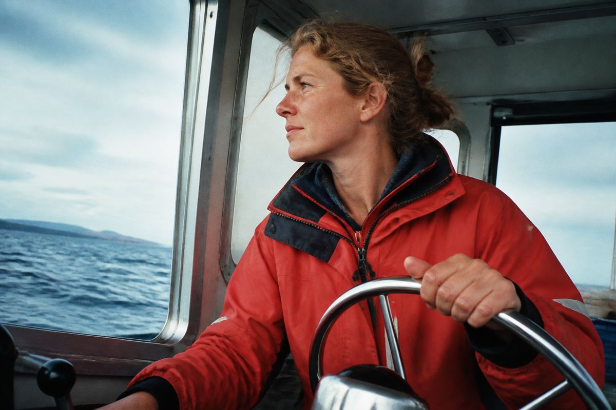 A marine biologist steering a research boat at sea