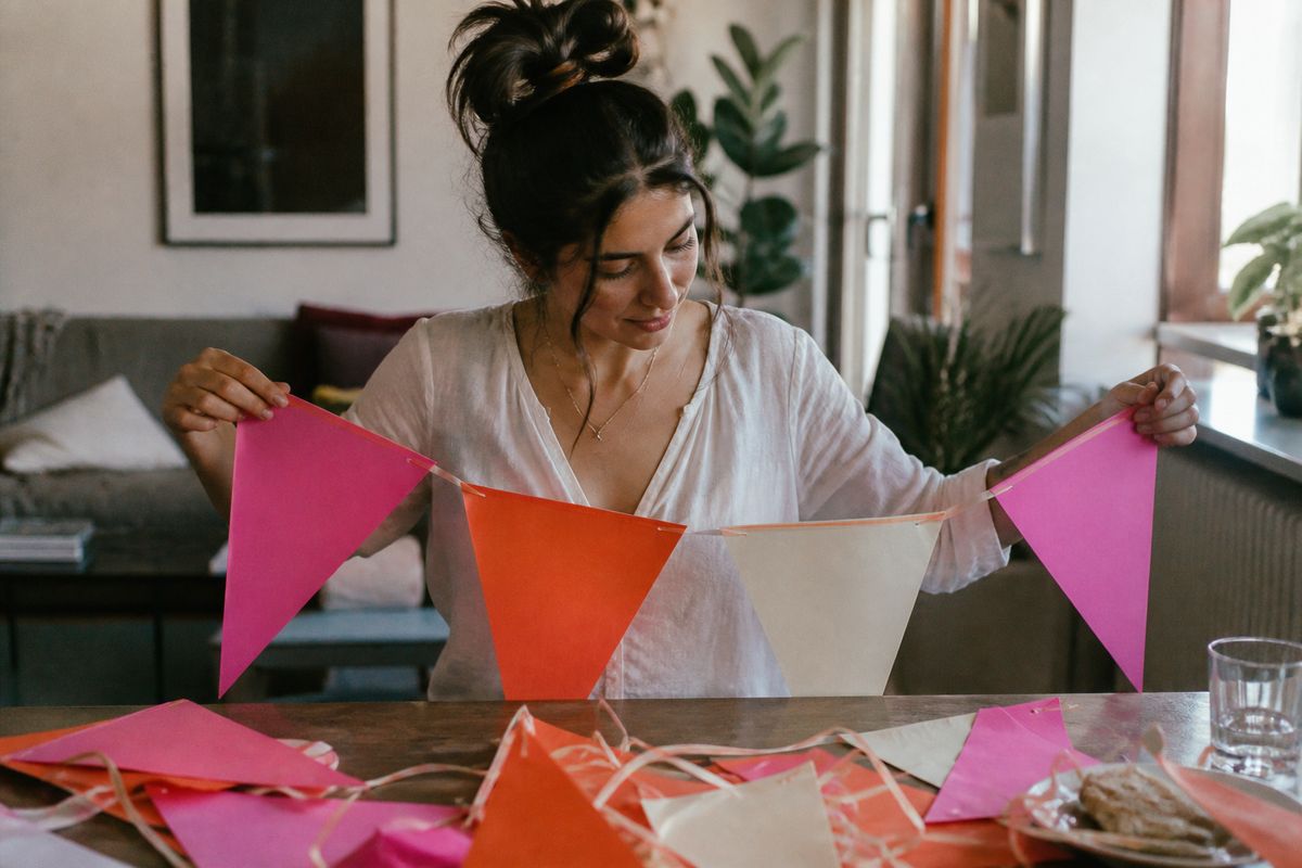 A woman assembling a colorful hen party banner at home