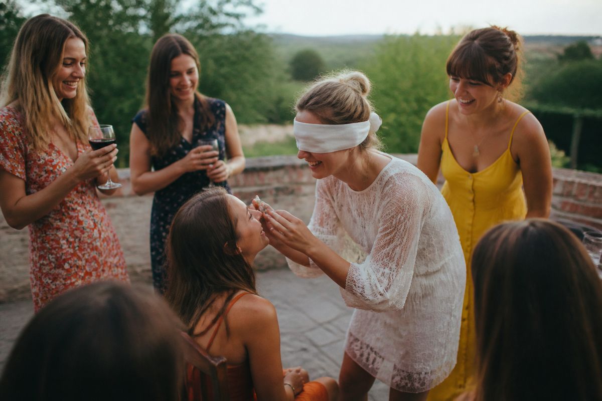 A group of women laughing while playing hen party games outdoors