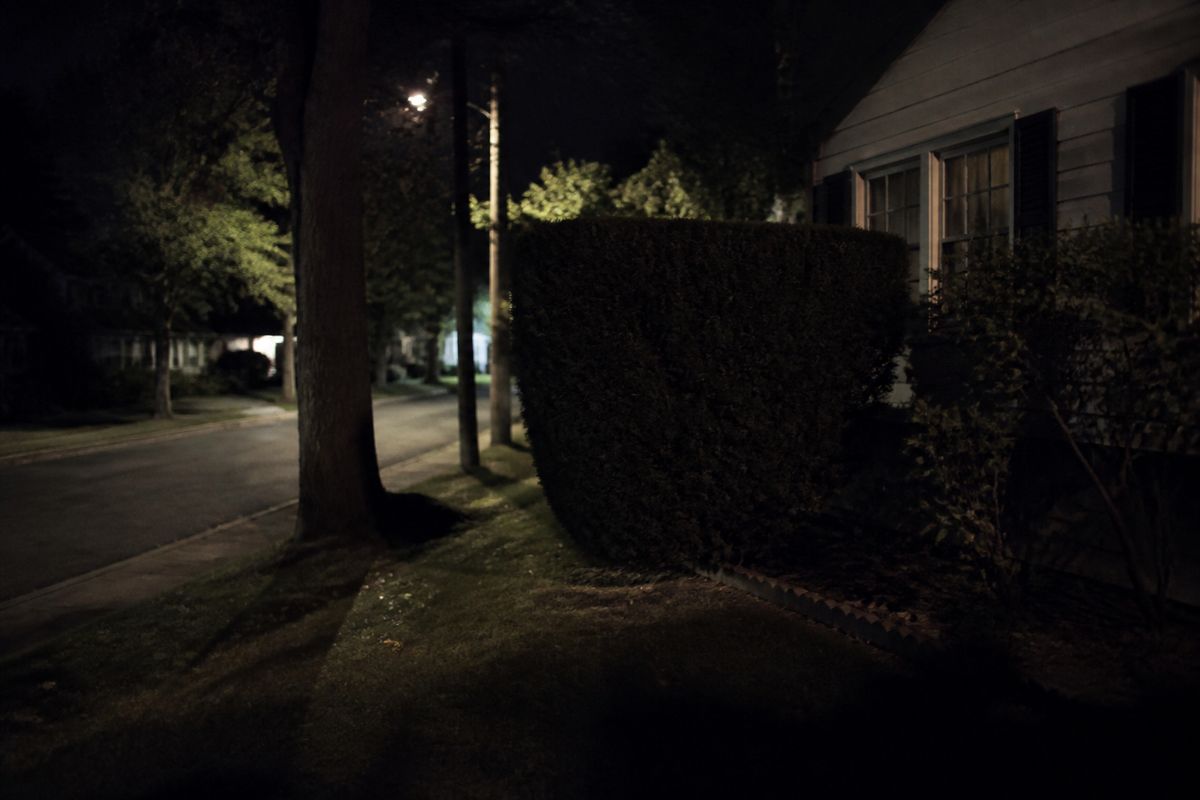 Dimly lit suburban street with eerie shadows and hiding spots