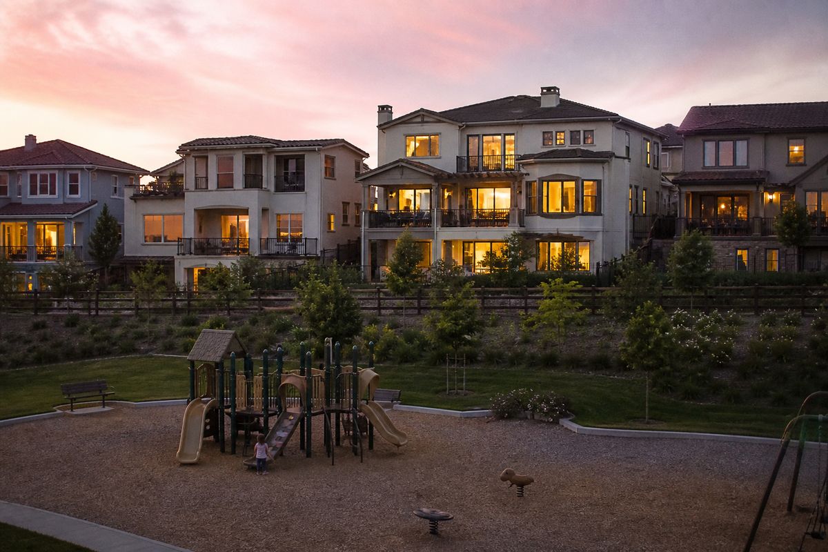 Multi-story suburban homes overlooking a playground at dusk