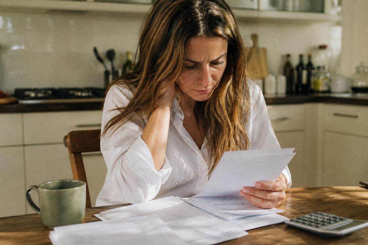 A person reviewing bank statements at a kitchen table.