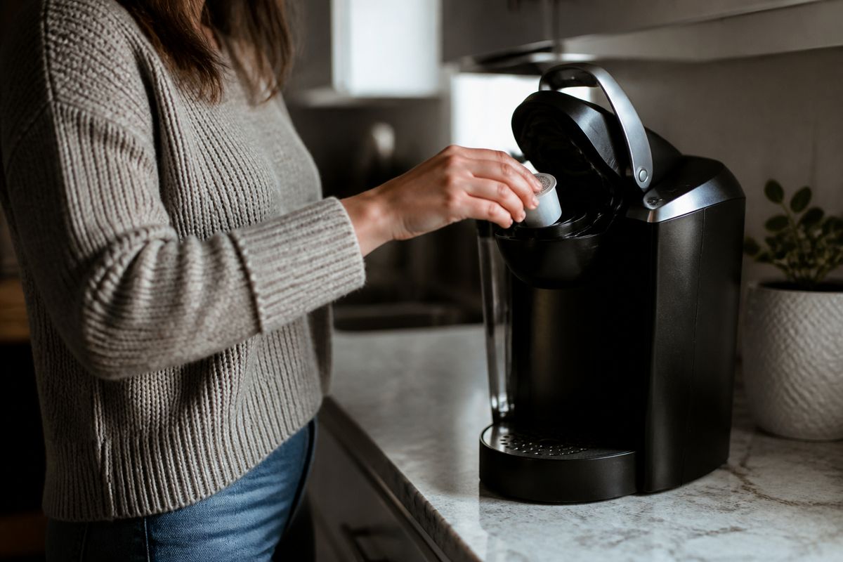 A person placing a cleaning pod into a Keurig coffee maker.