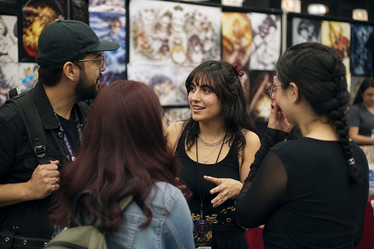 A group of fans chatting animatedly at a convention booth