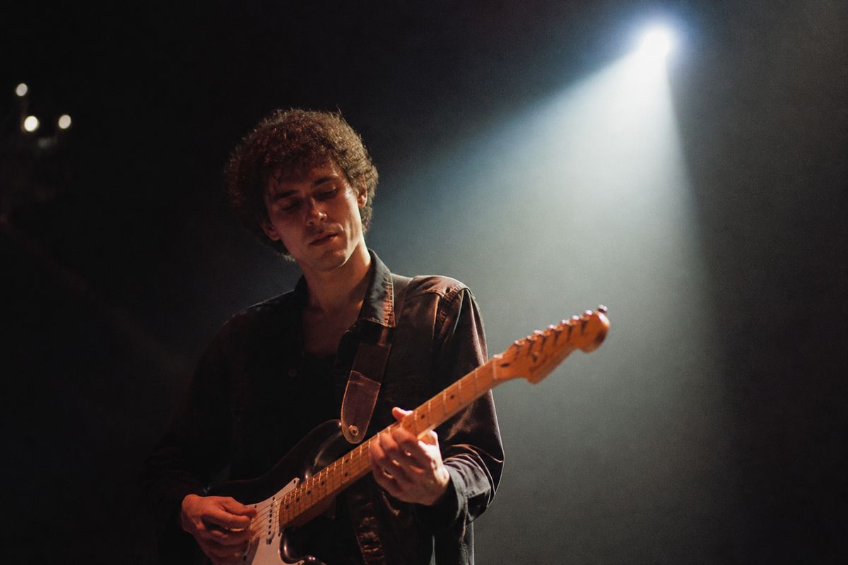A young musician performing on stage with a spotlight.