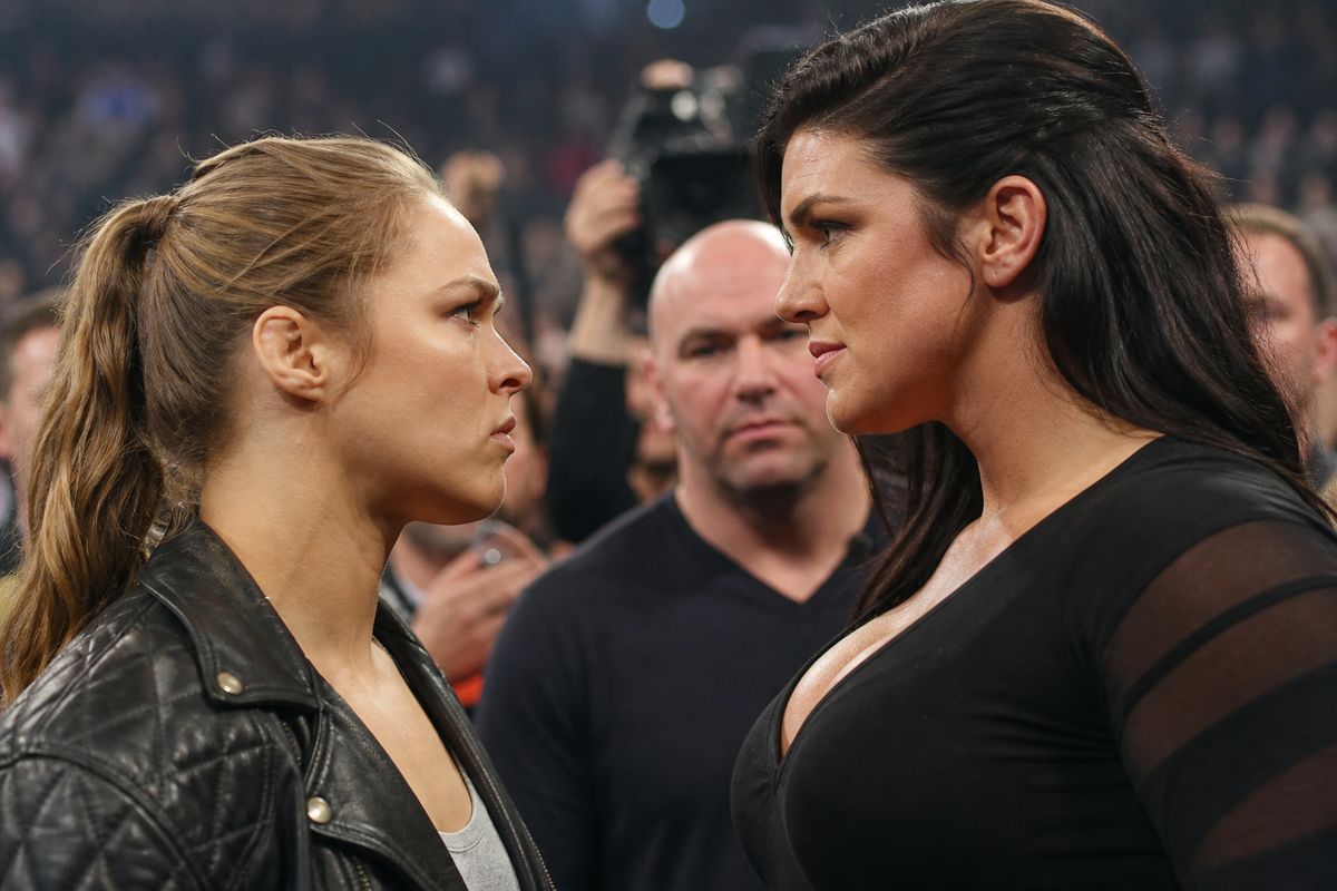 Ronda Rousey and Gina Carano facing off in a crowded arena.