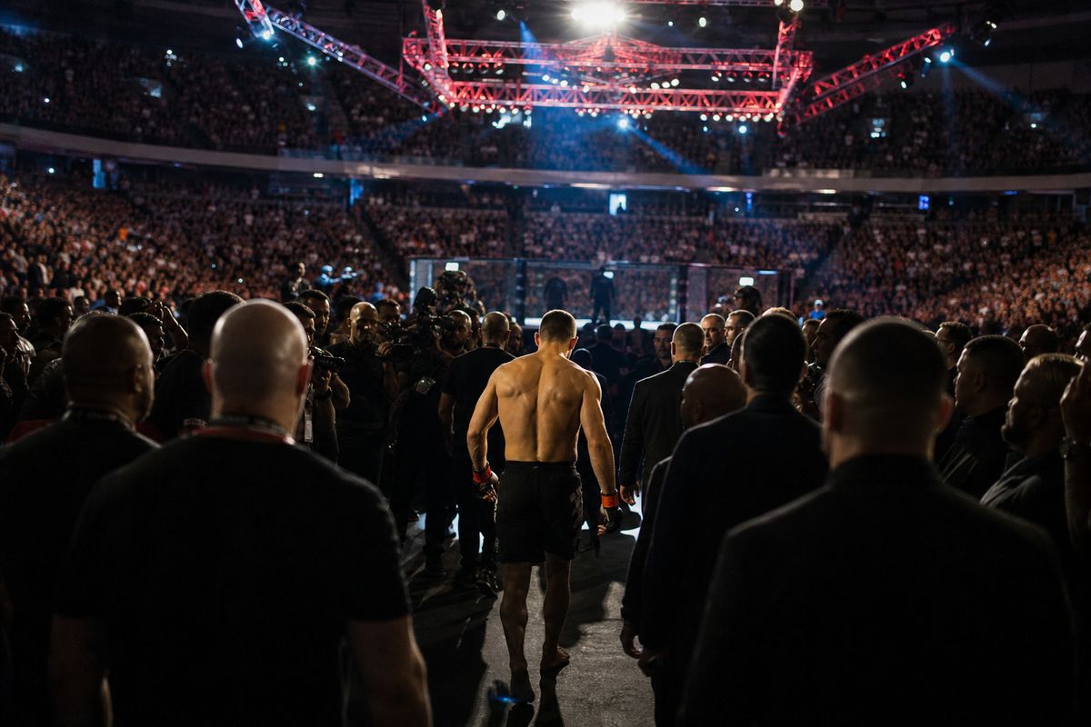 A packed arena with fighters entering the cage under bright lights
