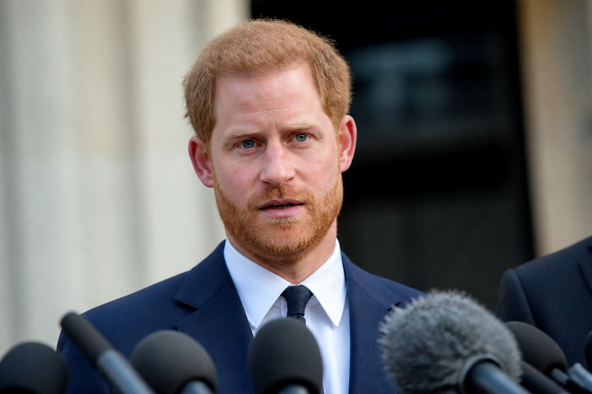 Prince Harry speaking at a press conference with microphones
