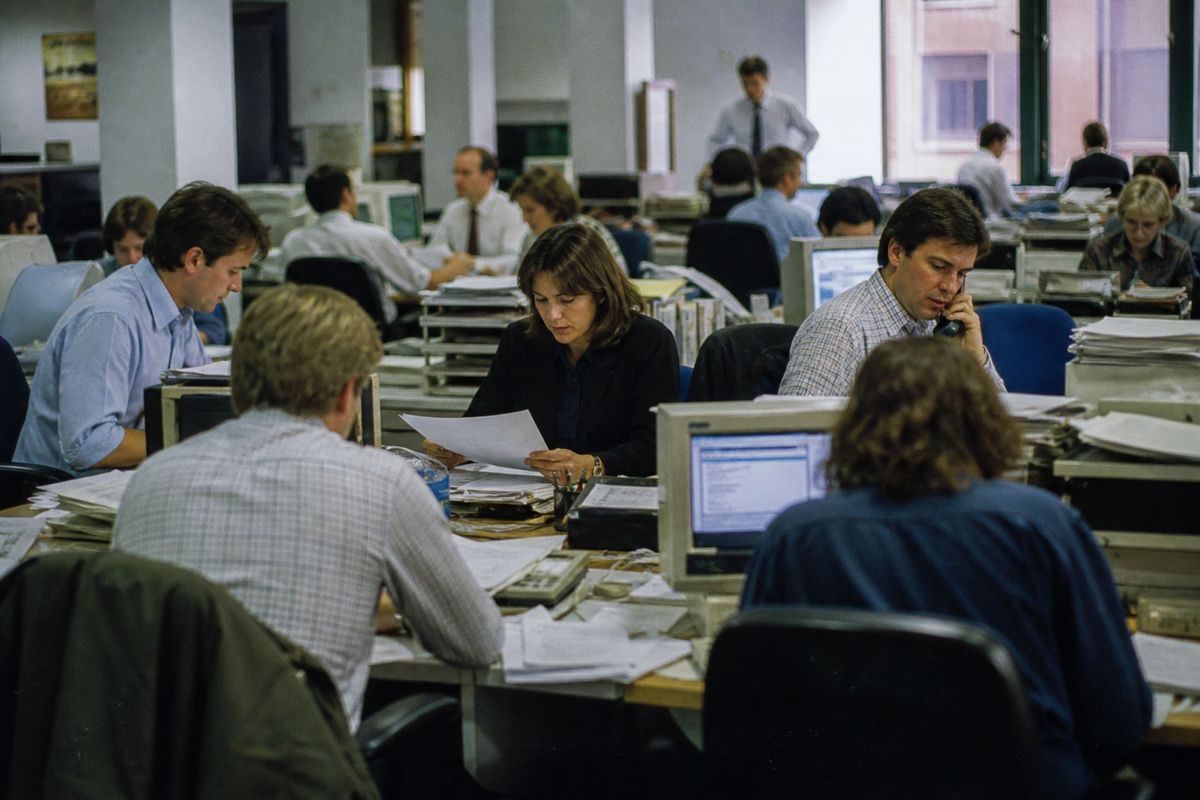 Journalists working inside a bustling British newsroom.