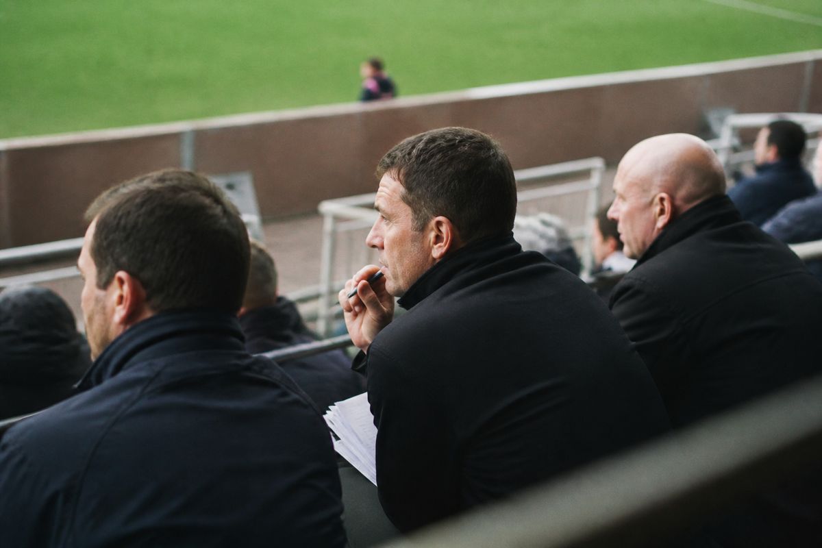 Club scouts watching overseas players during a match.