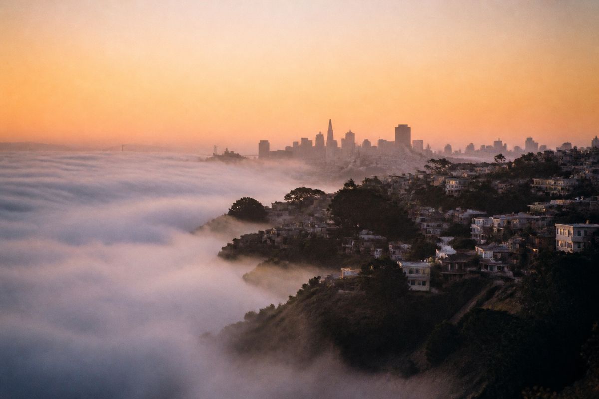 Fog rolling over San Francisco's hilly coastline at sunrise