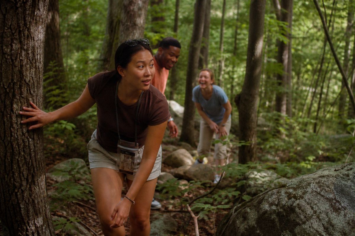 Participants excitedly searching a wooded trail during the scavenger hunt