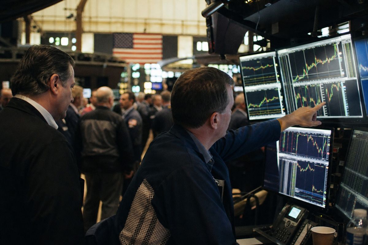 Traders watching multiple screens on a bustling exchange floor