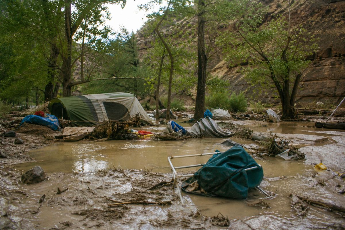 Flooded campsite with uprooted tents and debris scattered
