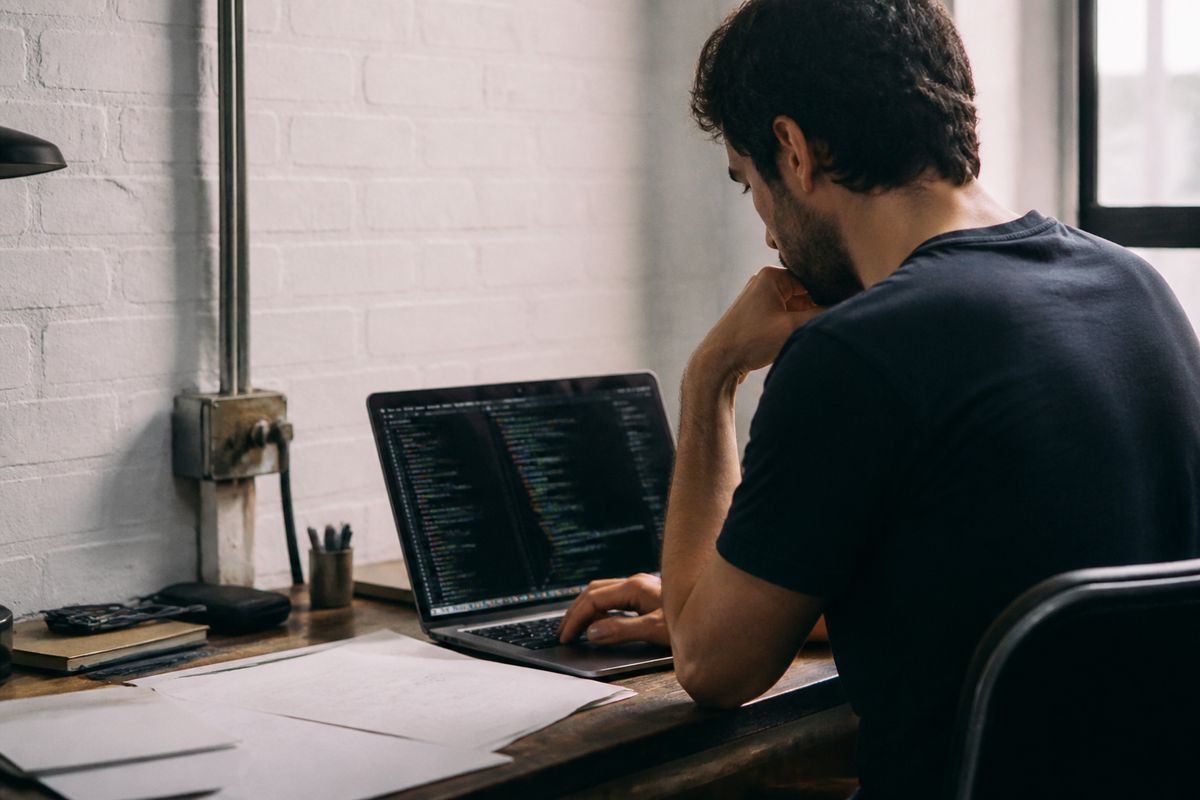 A web developer reviewing website code on a laptop screen