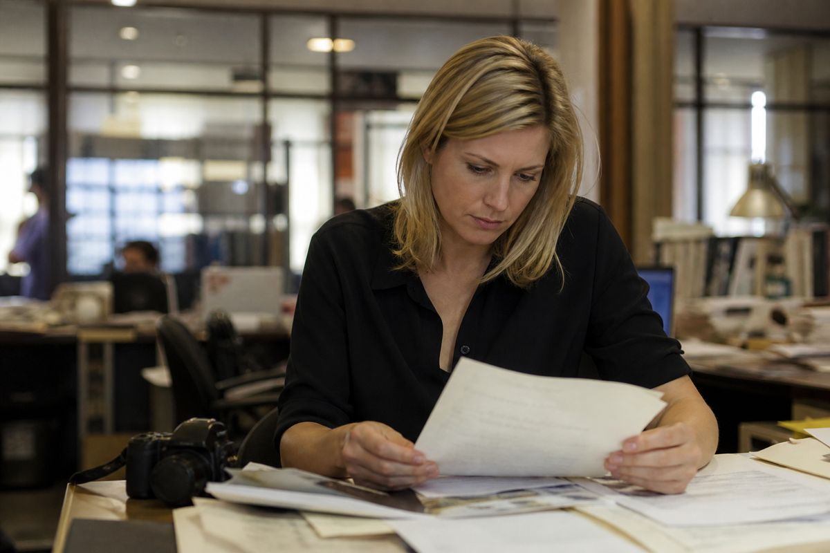 A reporter reviewing documents in a newsroom.
